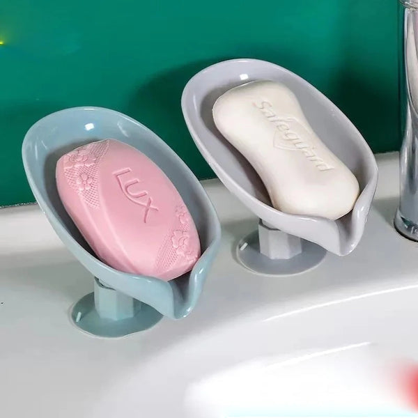 Two soap dishes holding pink and white soap bars on a bathroom counter.